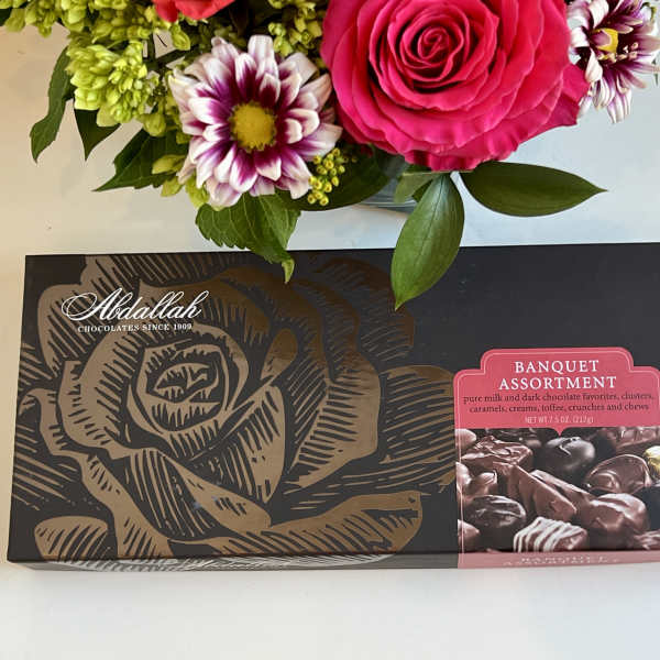 Bouquet above a box of assorted chocolates