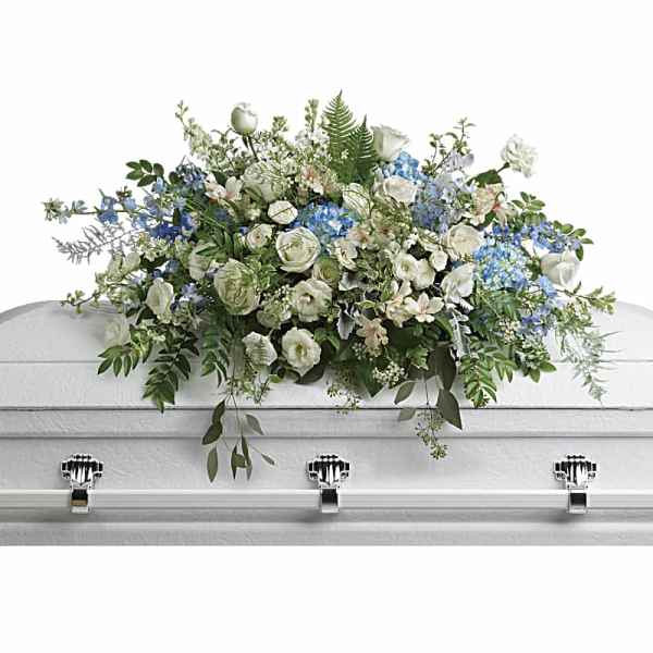 White and blue floral casket spray on a white casket