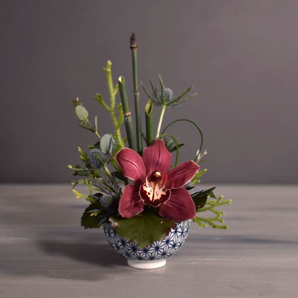 Small orchid arrangement in a patterned ceramic bowl