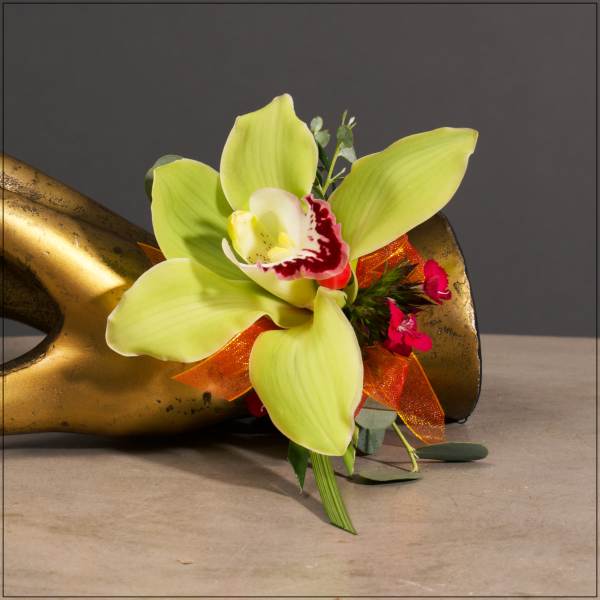 Lime green orchid bloom with orange ribbon on a gold sculpture