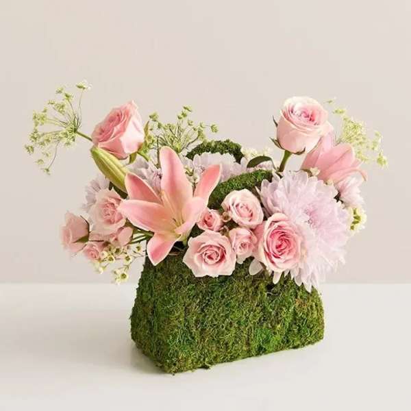 Pink roses and lilies arranged in a moss-covered rectangular container