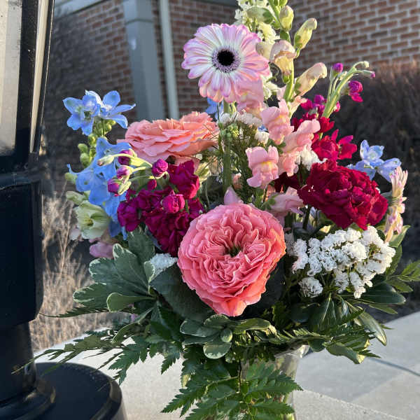 Mixed bouquet in a clear glass vase with pink, blue, and white blooms