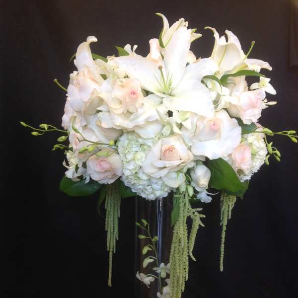 White lilies and pale pink roses in a tall glass vase