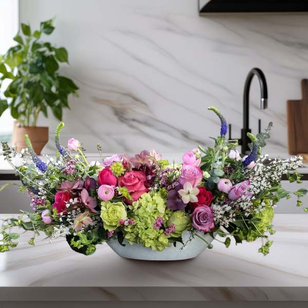 Low floral centerpiece with pink, purple, and green blooms in a shallow bowl