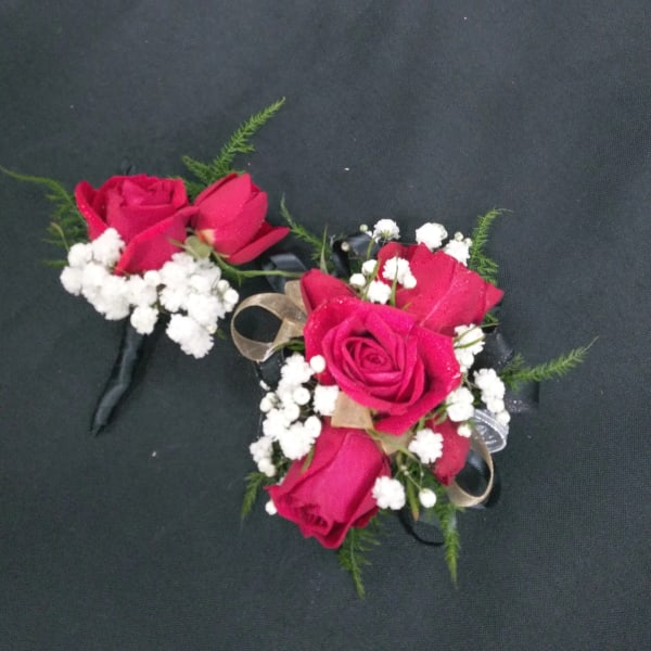 Two red rose corsages with white baby's breath on black ribbon