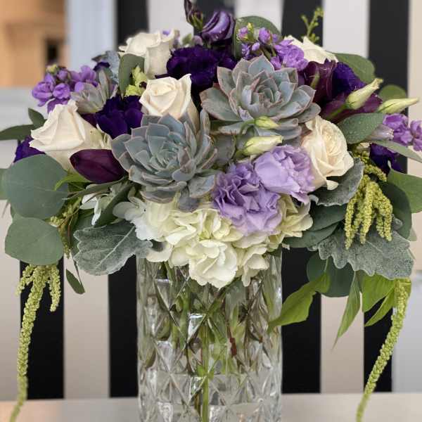 Purple and white floral arrangement in a clear glass vase