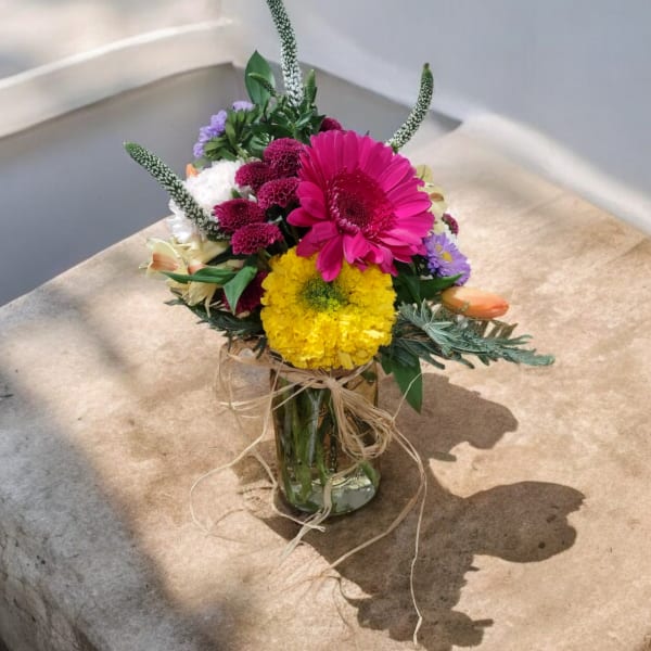 Mixed bouquet in a glass vase with bright pink and yellow blooms