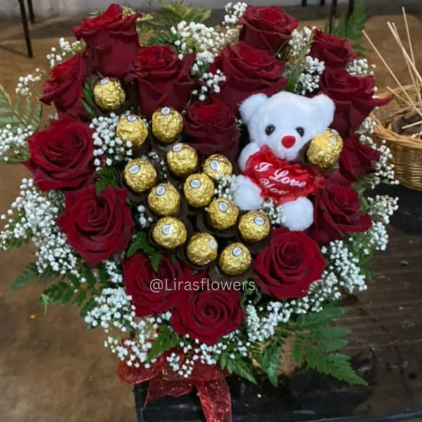 Heart-shaped bouquet of red roses with a teddy bear and gold chocolates