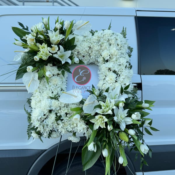 White floral funeral wreath with lilies and chrysanthemums on a stand