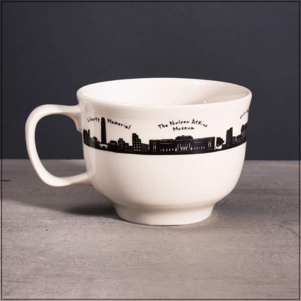 White ceramic mug with a black city skyline and labeled landmarks around the rim.