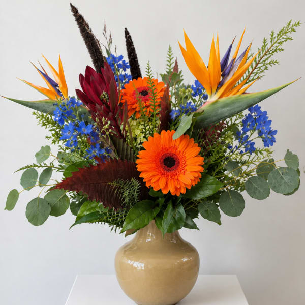 Bright mixed bouquet in a beige vase with orange and blue flowers