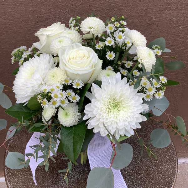 Compact white bouquet with roses, chrysanthemums, and asters accented with eucalyptus and a white ribbon