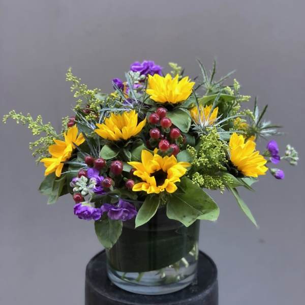 Yellow sunflowers and purple flowers in a glass vase