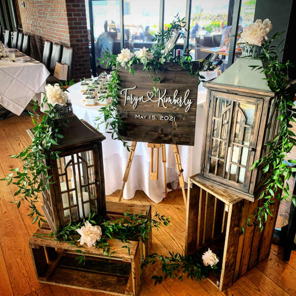 Wedding display with a wooden sign, lanterns, and cream flowers