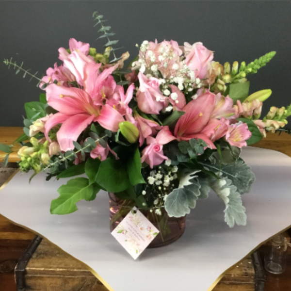 Pink lilies and roses arranged in a glass vase