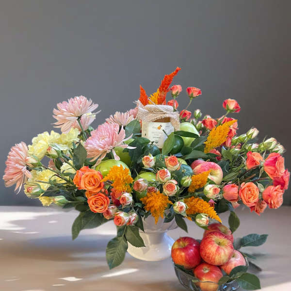 Mixed bouquet in a white vase with apples and a small bowl of apples