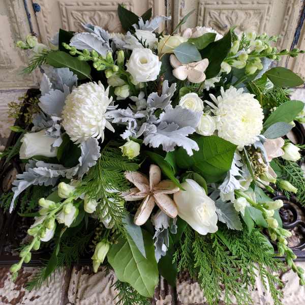 White floral arrangement with roses, mums, and greenery