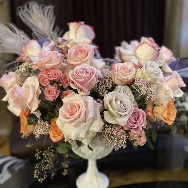 Bouquet of pastel roses in a white pedestal vase