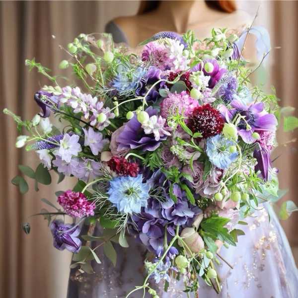 Large bouquet of purple, blue, and pink flowers held by a person