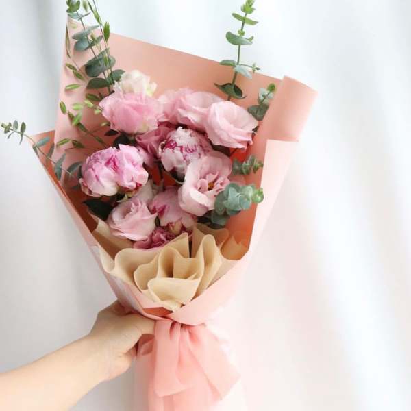 Pink bouquet with peonies and eucalyptus wrapped in peach paper