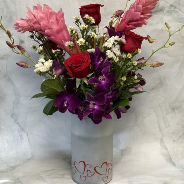 Bouquet of red roses and purple orchids in a heart-decorated vase