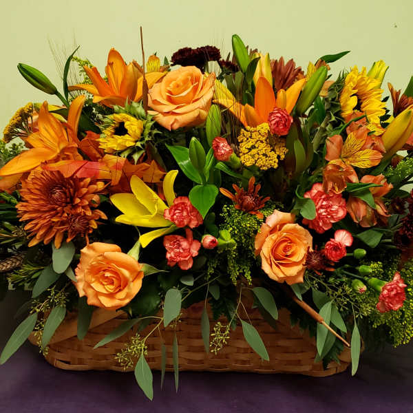 Basket arrangement of orange and yellow flowers with roses and lilies