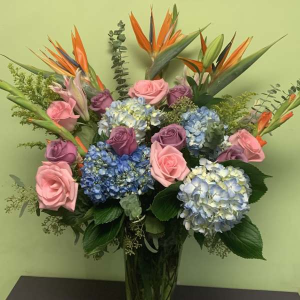 Bouquet of pink and purple roses with blue hydrangeas in a glass vase