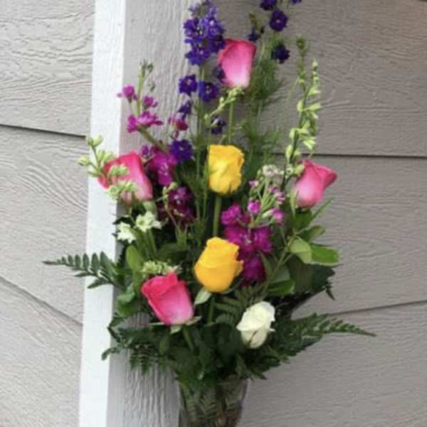 Tall bouquet of pink, yellow, white, and purple flowers in a glass vase