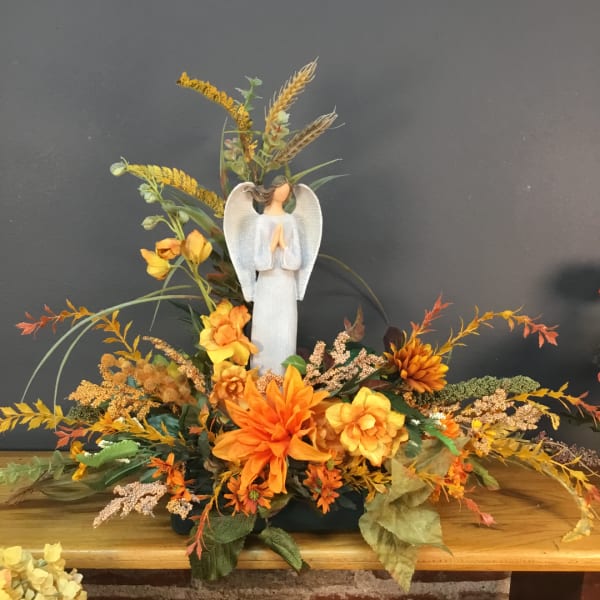Autumn floral arrangement with an angel figurine and orange flowers