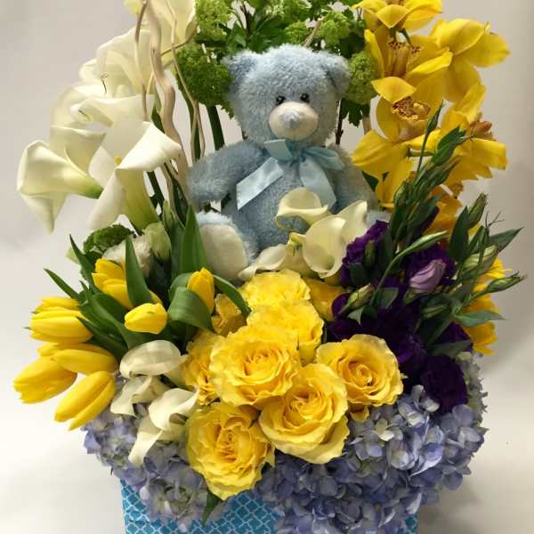 Flower arrangement with a teddy bear, yellow roses, calla lilies, and orchids