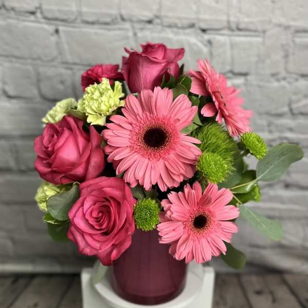 Pink roses and gerbera daisies arranged in a purple vase