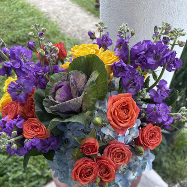 Colorful bouquet of roses, purple stock, and blue hydrangeas in a vase