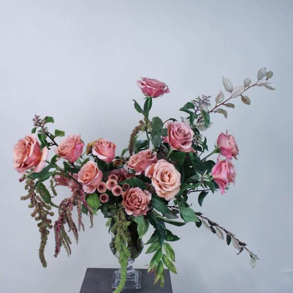 Pink roses arranged in a clear glass vase with trailing greenery
