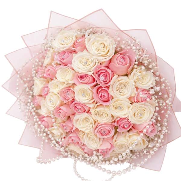 Pink and cream rose bouquet wrapped in pale pink paper with pearl accents