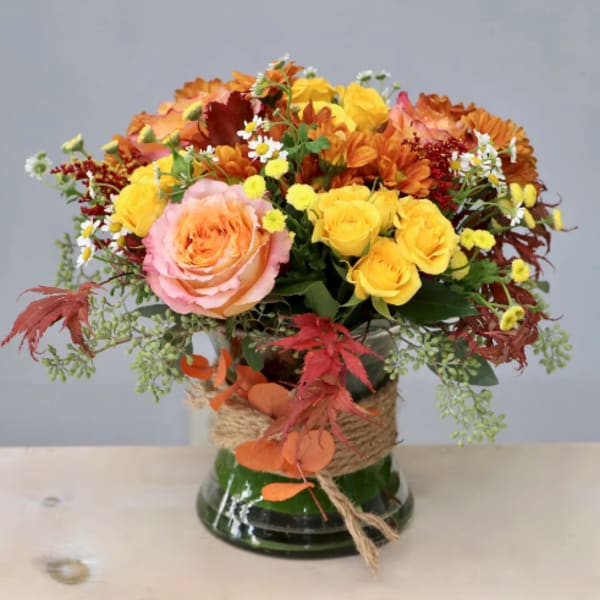 Autumn bouquet of roses and daisies in a glass vase