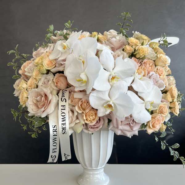 Bouquet of pale roses and white orchids in a white vase