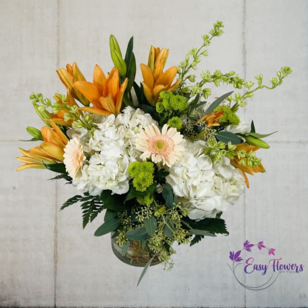 Orange lilies and white hydrangeas in a glass vase