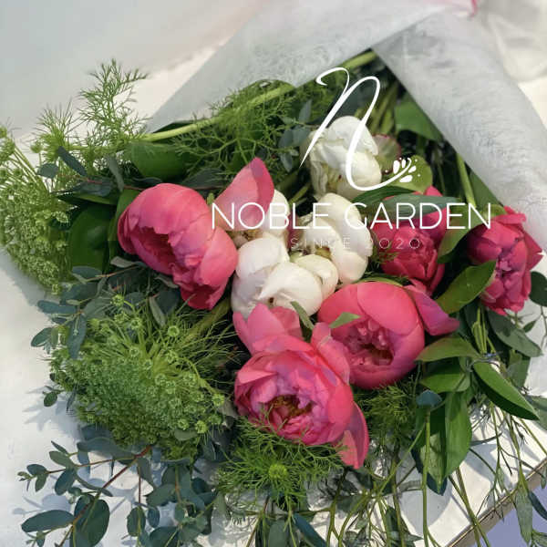 Bouquet of pink and white peonies with greenery wrapped in paper
