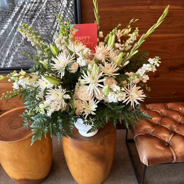 White floral arrangement in a white vase with a birthday card