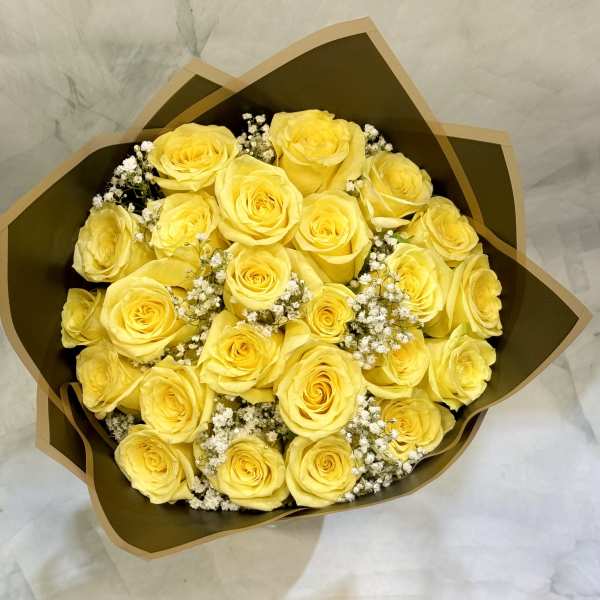 Bouquet of yellow roses with white filler flowers in brown wrap