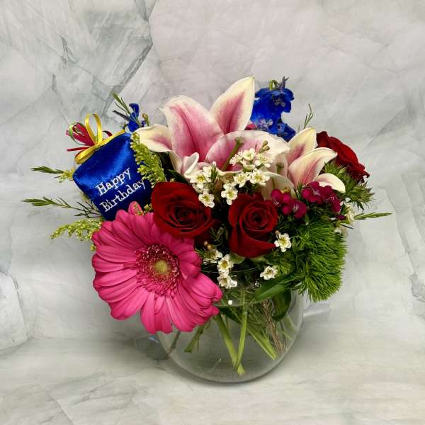 Mixed bouquet in a glass vase with a birthday tag