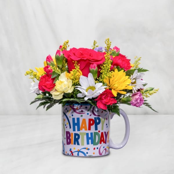 Mixed bouquet in a birthday mug with pink, yellow, and white flowers
