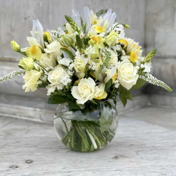 White and yellow floral arrangement in a round glass vase