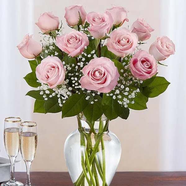 Pink roses arranged in a clear glass vase with baby's breath
