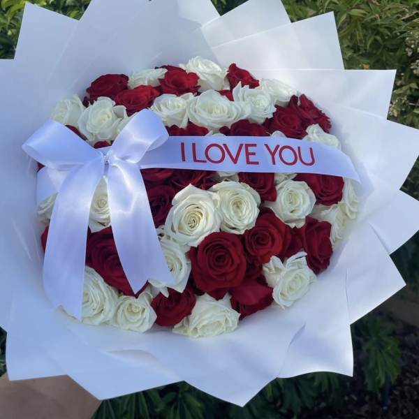 Heart-shaped bouquet of red and white roses wrapped in white paper with an I LOVE YOU ribbon.