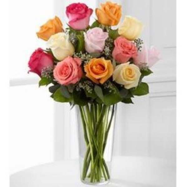 Tall clear vase of mixed pink, peach, yellow, and cream roses