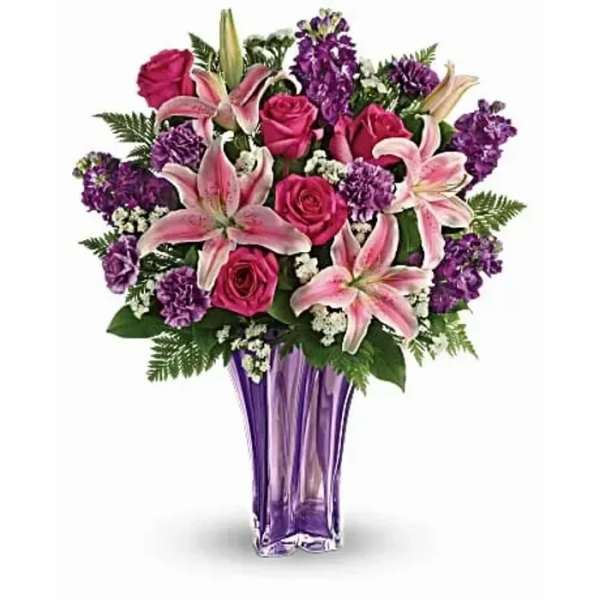 Pink roses and lilies in a purple glass vase