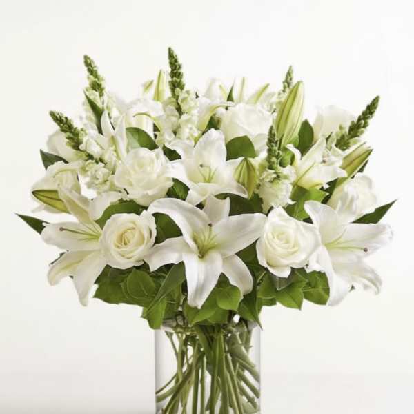 White lilies and roses arranged in a clear glass vase