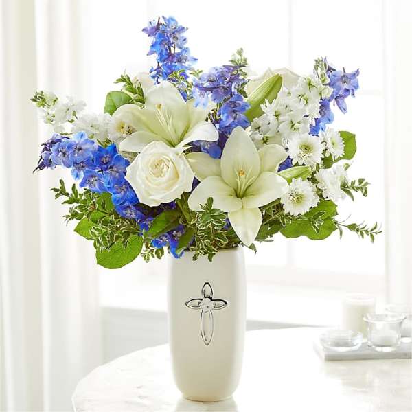 White lilies and roses with blue flowers in a white vase