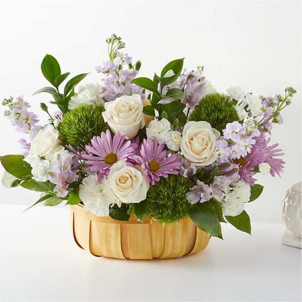Mixed bouquet of roses and purple daisies in a woven basket